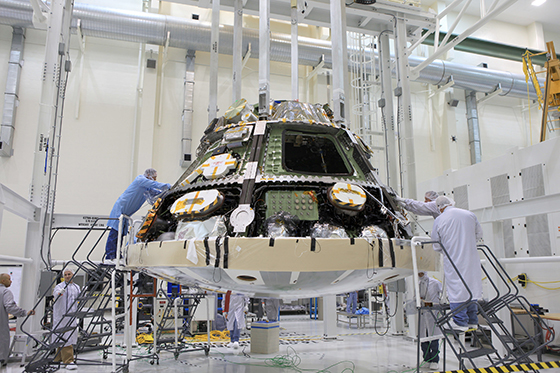 Lockheed Martin technicians and engineers attach the heat shield to the Orion crew module inside the Operations and Checkout Building high bay at NASA's Kennedy Space Center in Florida. Photo credit: NASA/Daniel Casper
